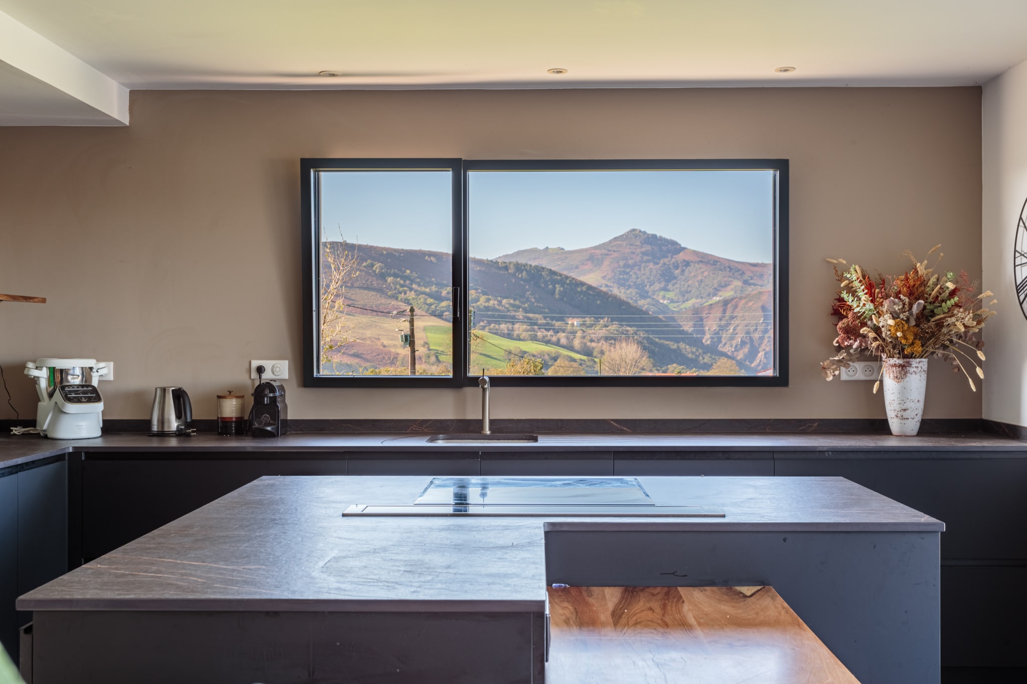 Vue panoramique intérieure d'un châssis fixe avec un ouvrant oscillo-battant en aluminium gamme Simple dormant visible, intégré dans une maison neuve à Itxassou