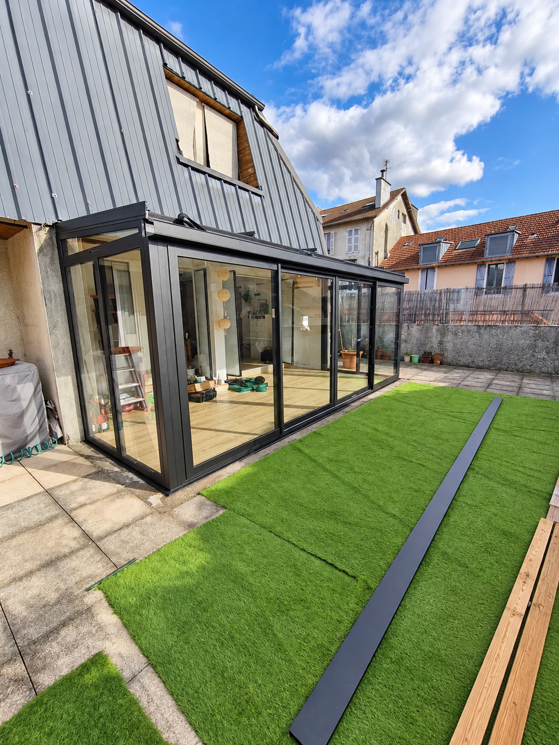 Vue extérieure en perspective de la véranda aluminium noir sablé contre la maison à Pau